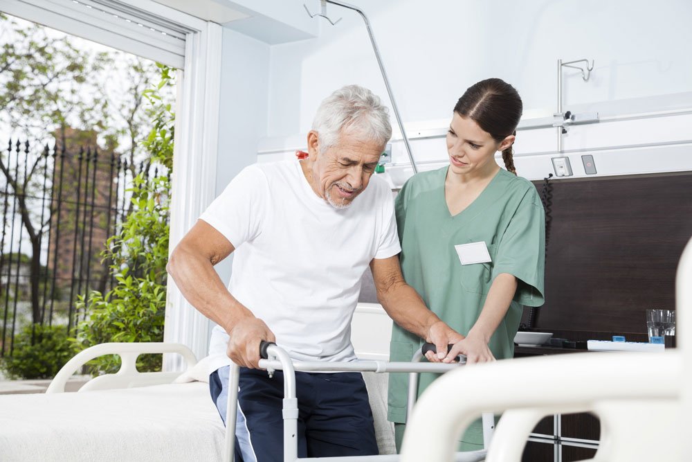 A nurse in a senior care community helps a senior with a walker.